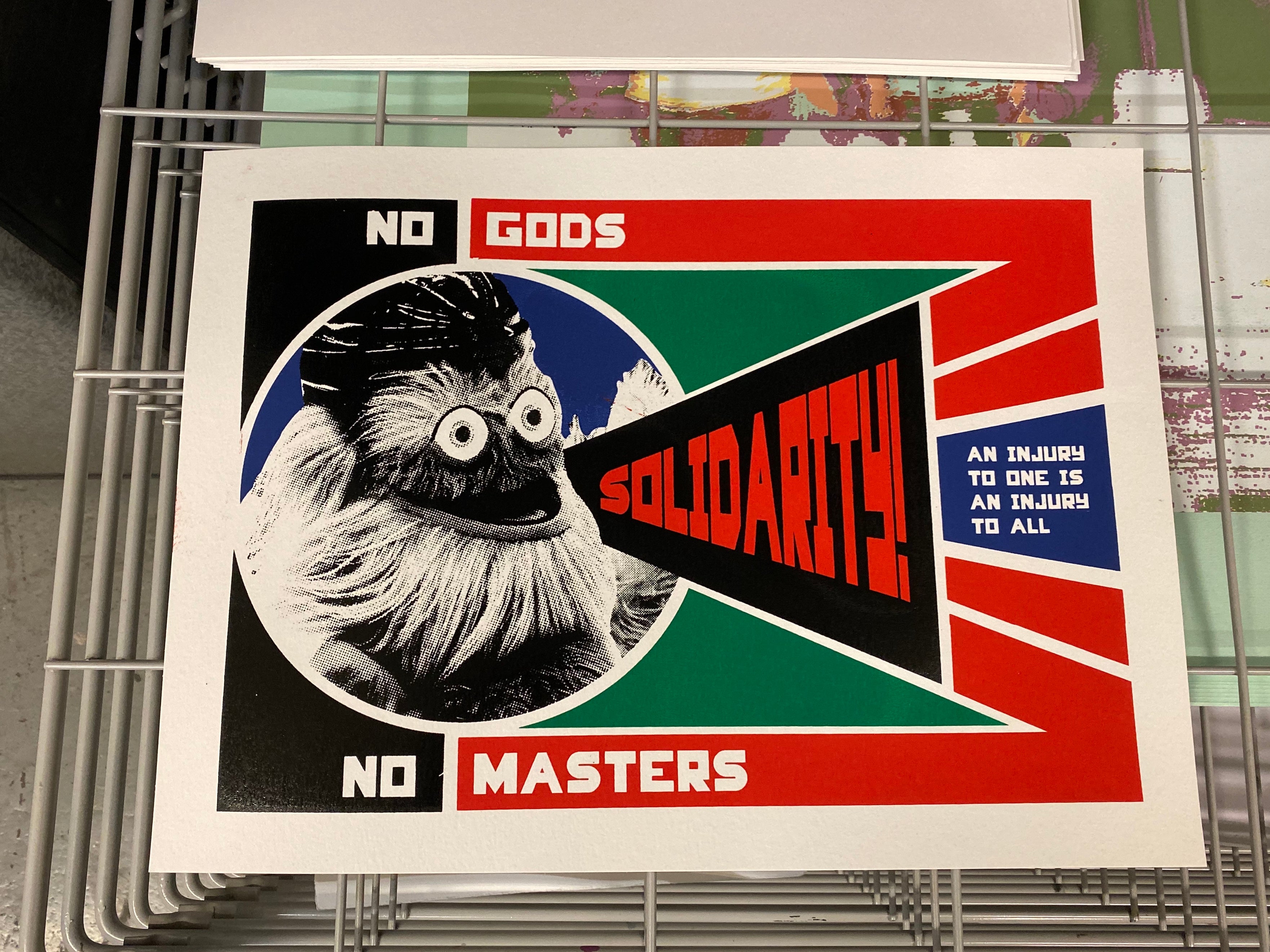 A color screen print image of Philadelphia Flyers Mascot Gritty with the words "No Gods. No Masters. Solidarity. An injury to one is an injury to all."